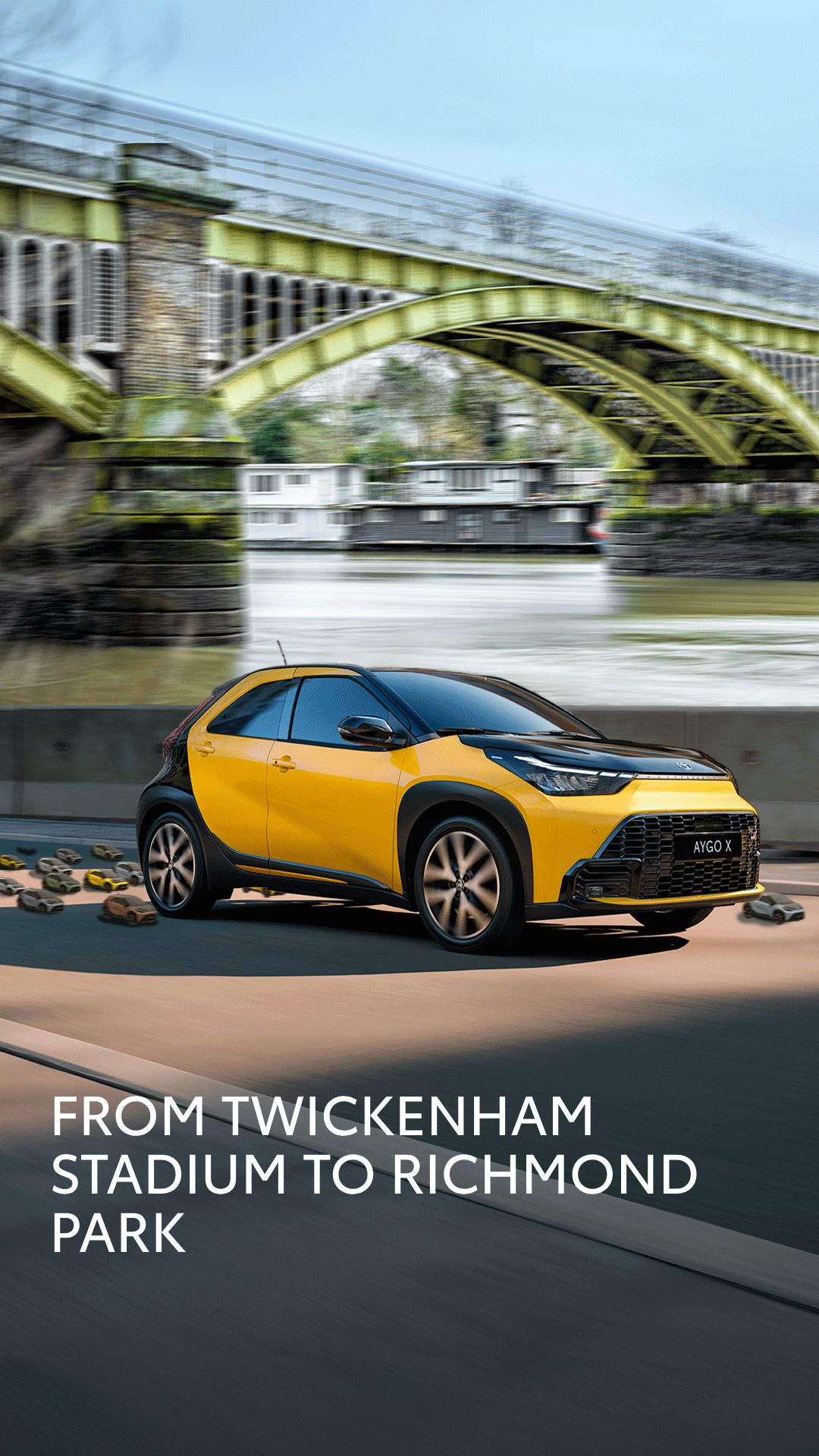 Yellow compact SUV driving on a road beside a river with a green arched bridge in the background; bold white promo text at bottom reads 'From Twickenham Stadium to Richmond Park'